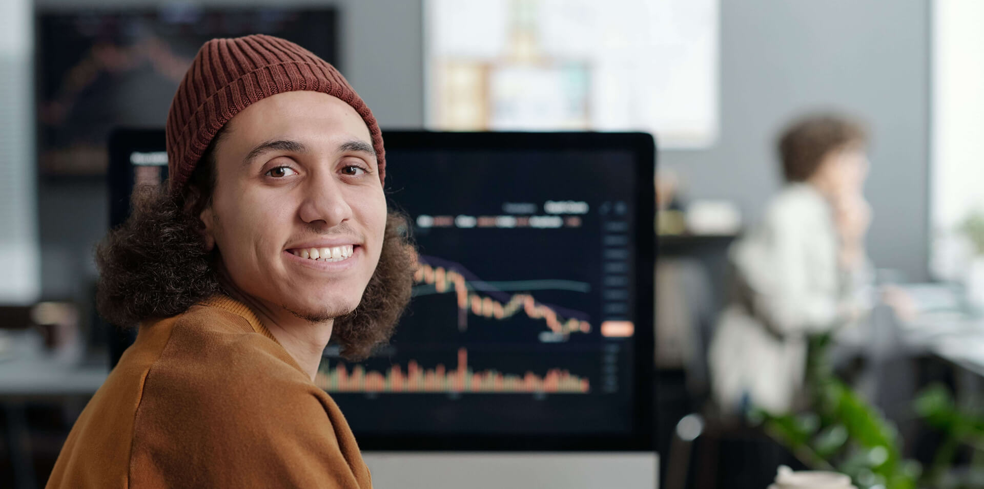 Smiling student sitting in front of a computer screen displaying data charts during Data Analyst Diploma training