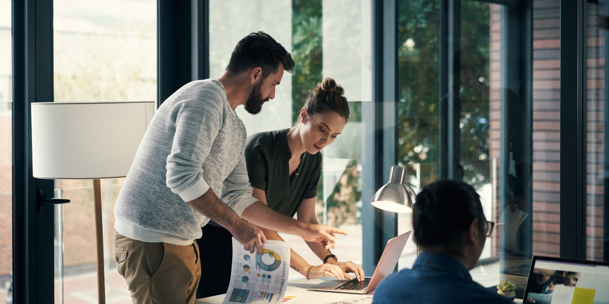 Two colleagues analyzing business charts and data together in a modern office, reviewing financial information that helps employers understand UK minimum wage requirements and their impact on payroll planning.