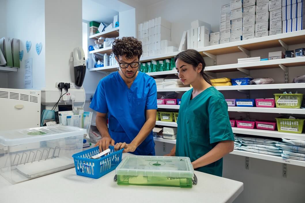 Two healthcare trainees in scrubs working together in a medical supplies room as part of medical administration training