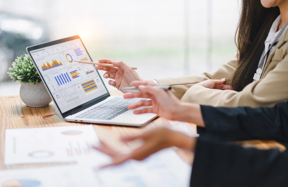 Hands pointing at laptop screen displaying Power BI dashboards and charts during Microsoft Power BI training