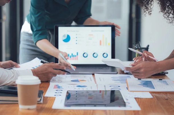 Team collaborating on data reports and visualisations with Power BI dashboards displayed on a laptop during Microsoft Power BI training
