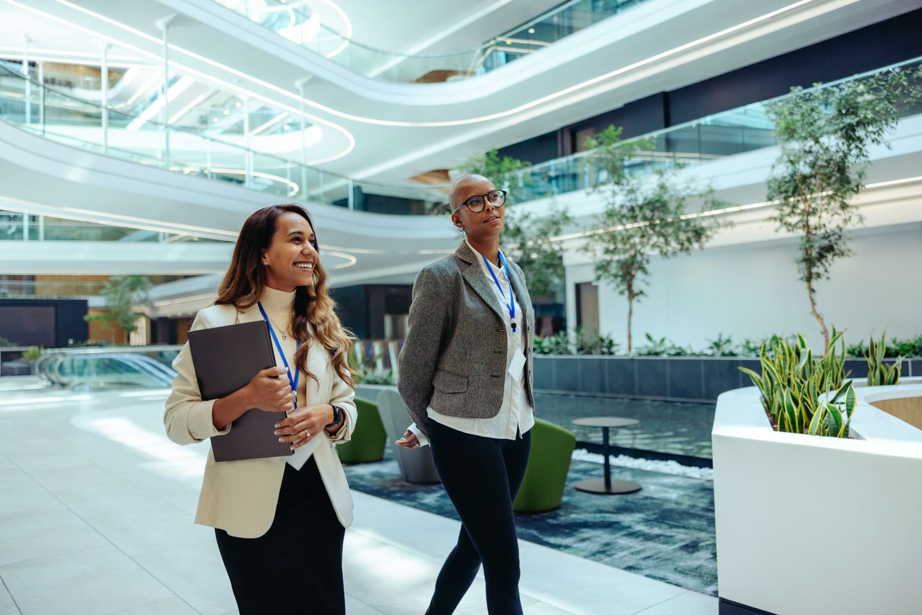 Two business professionals walking through a modern eco-friendly office building, representing careers in sustainability and corporate responsibility
